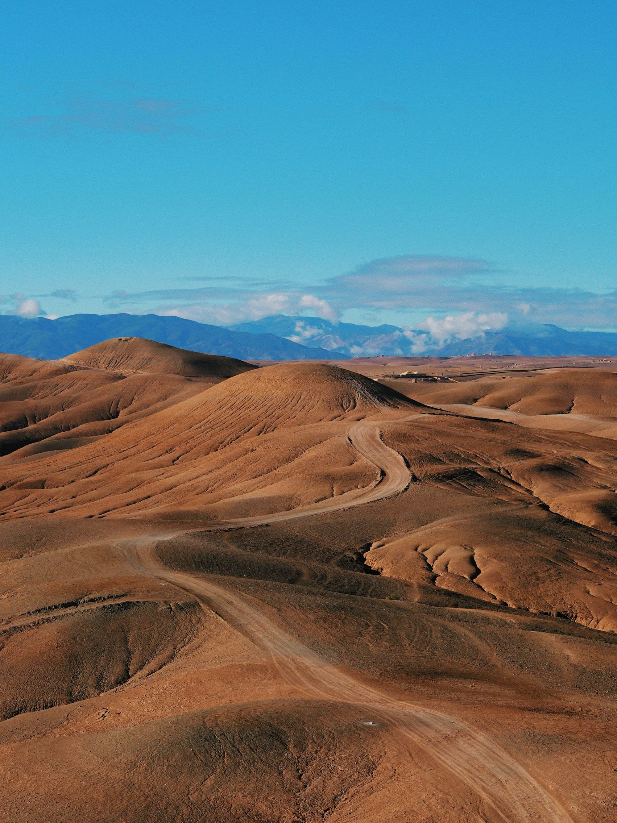 Collines ocre du désert d'Agafay avec l'Atlas au loin